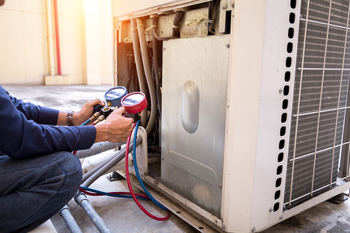 A person using a blue and red gauge to test an air conditioning unit in El Paso.