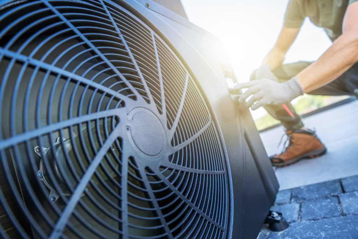 A person wearing gloves inspecting an outdoor HVAC system in El Paso.